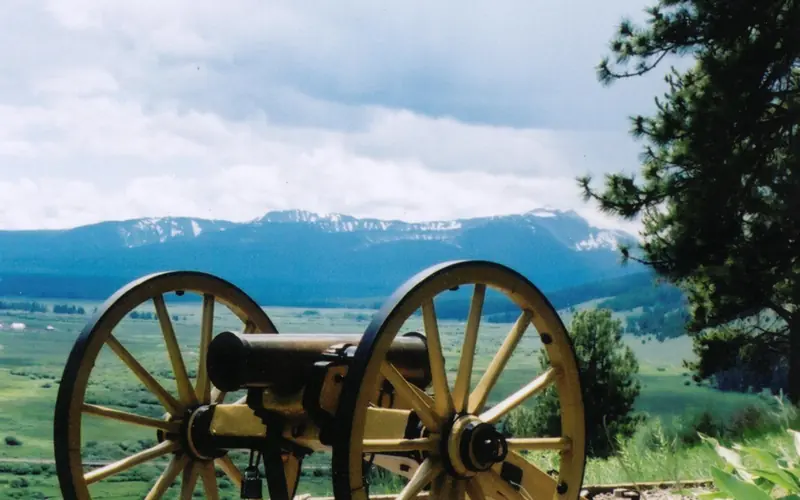 a cannon overlooks a valley and distant mountains