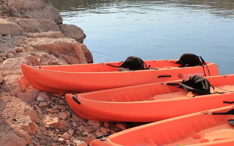 Four orange kayaks laying with their tips on the red rocks at Barry's Landing.