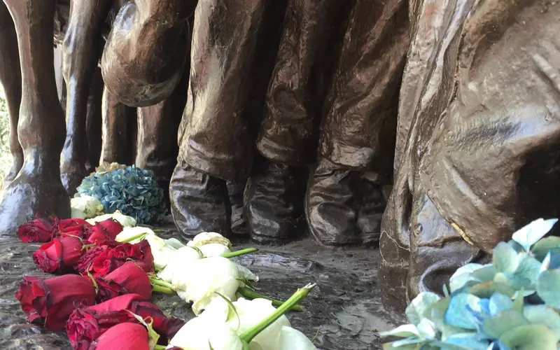 A close up image of flowers laid at the feet of the soldiers on the Shaw Memorial