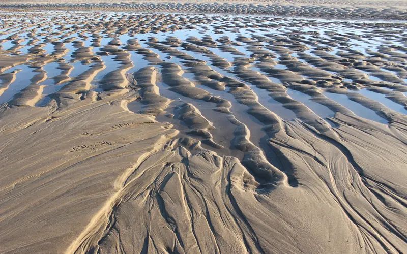 Low tide exposes rippled ridges of sand and water.