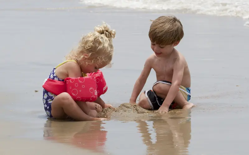 Two kids play in the sand.
