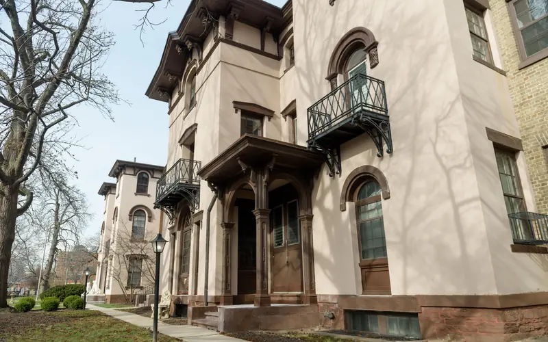 A tan and brown building, built in the Italian Villa style with rounded arches and balconies.