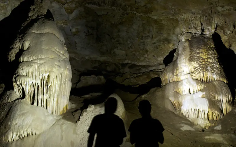 Two cavers inspect a series of calcite cave formations