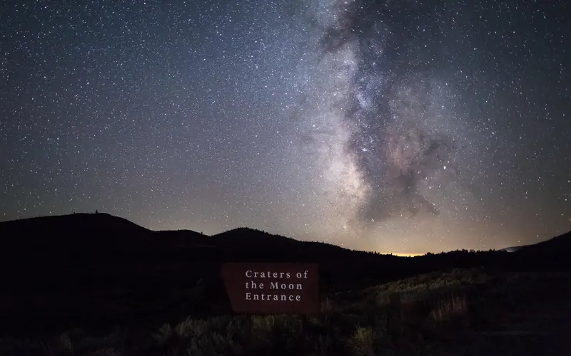 The Craters entrance sign sits below a starry night sky, with the milky way brightly-lit.
