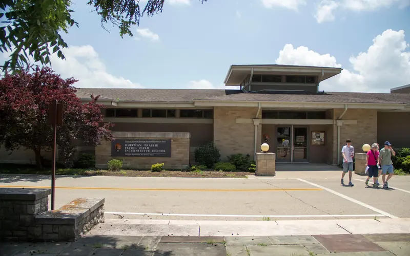 A one story stone building with a small tower jutting out of the middle and three people walking out