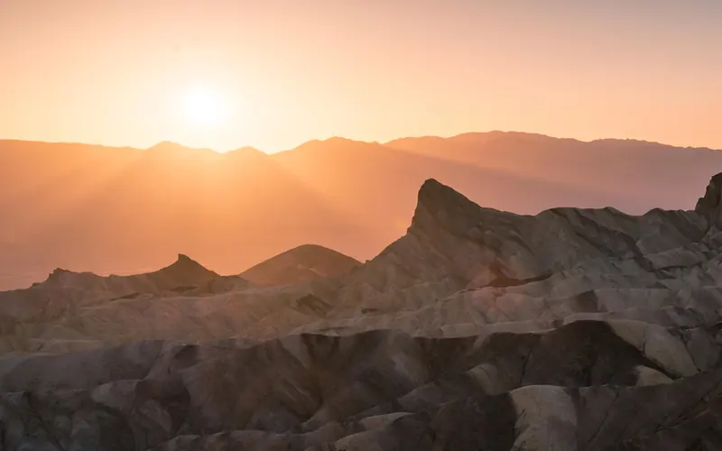 badlands bathed in pale pink and orange light from the setting sun