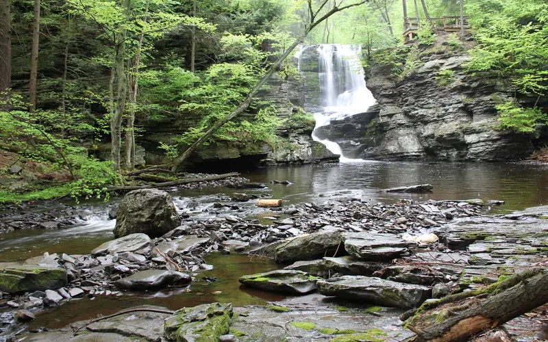 A waterfall flows toward the viewer along a rocky riverbed.