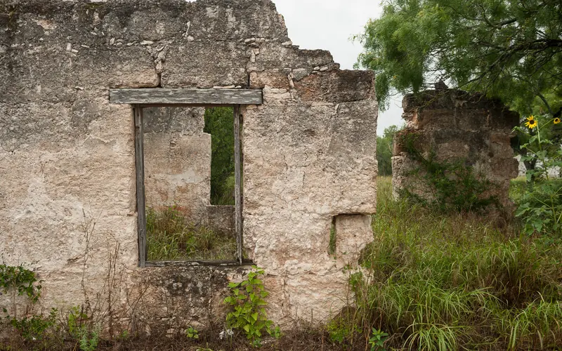 stone house ruins; briliant green grasses and trees on the right