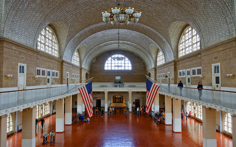 Great Hall has terra cotta-colored tile floor, a balcony, large arched windows, and vaulted ceiling