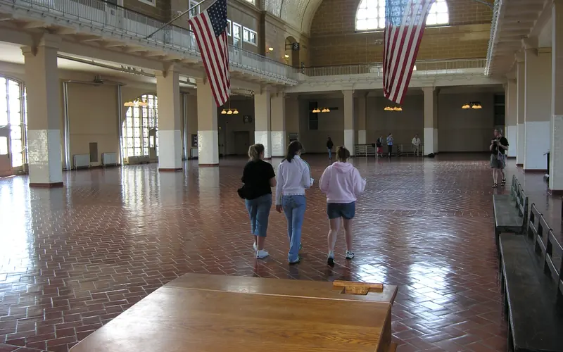 Honey oak colored tall desk on tiled floor in Great Hall with arched windows and vaulted ceiling.