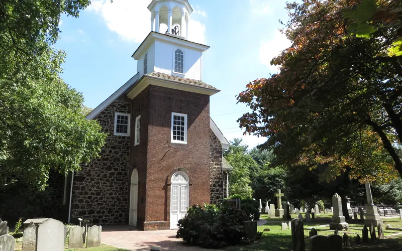 A brick bath leads to a door of an old church surrounded by vegetation.
