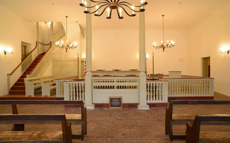 Pews line the side of the room leading to the English style court room.