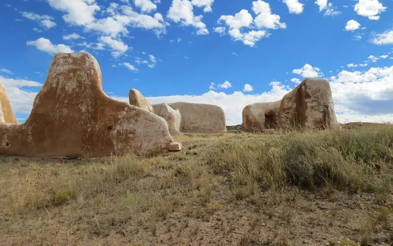 Ruins of adobe building under a blue sky with white clouds.