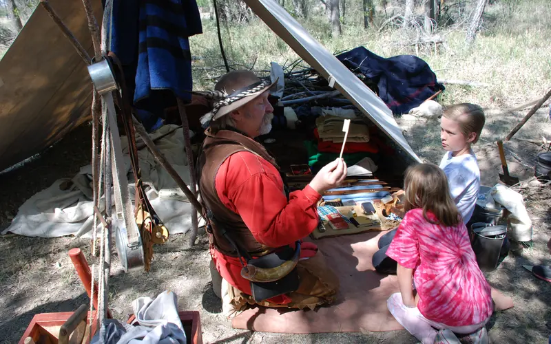 Living history interpreter explaining the life of a trapper/trader to young visitors