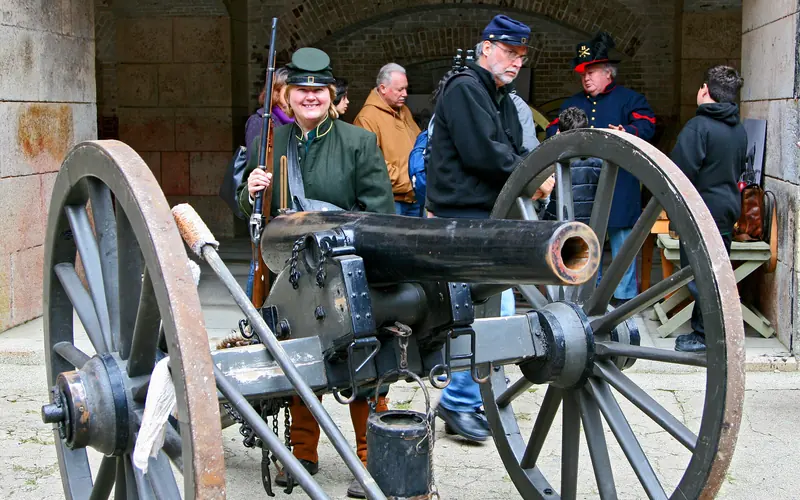 A cannon stands in front of Civil War re-enactors talking to the public.