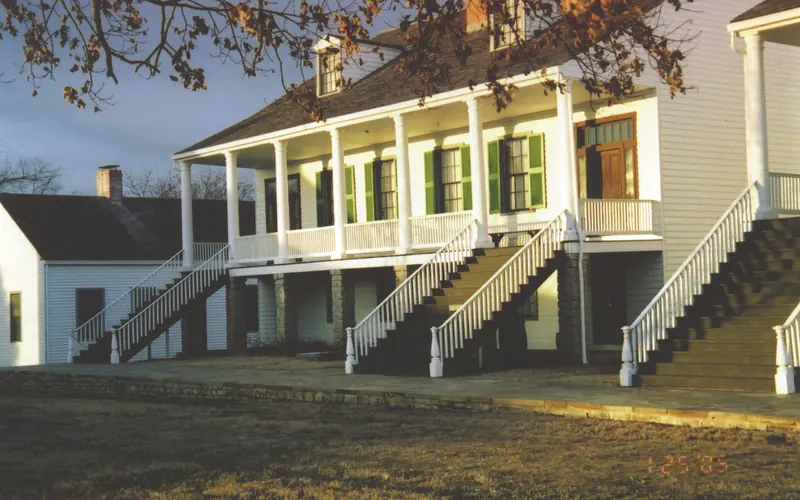 Wood frame structures with stairs next to a stone walkway. Structures reflect afternoon sunlight.