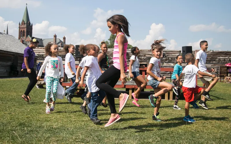 Children dance, jump, and skip on the parade ground of reconstructed Fort Stanwix.