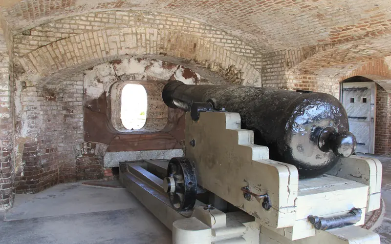 Civil War cannon sitting on carriage pointing towards firing hole in brick wall