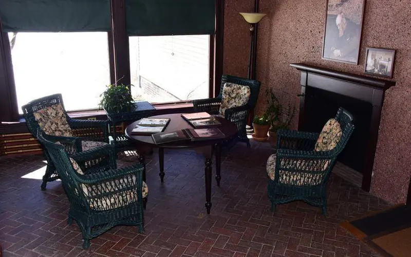 Wicker chairs around table in room with rock covered wall with views outside