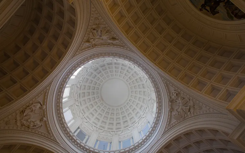 A circular dome is held up by carvings of allegorical figures.
