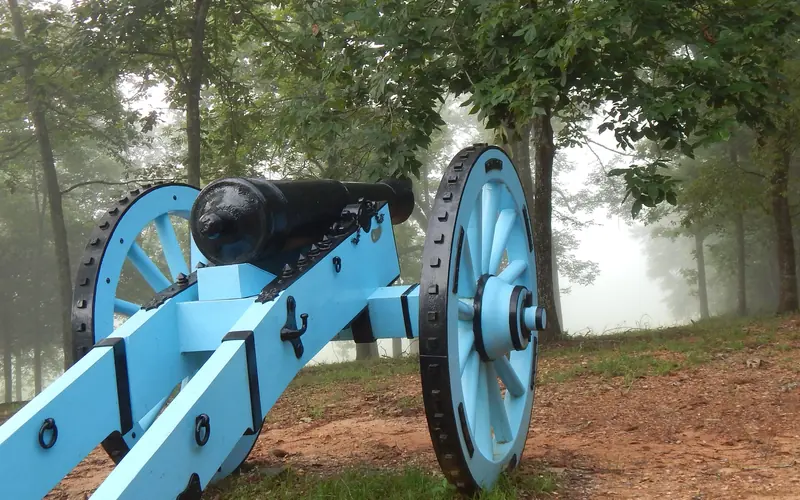 A blue painted 6-pounder cannon sits on hill facing the battlefield