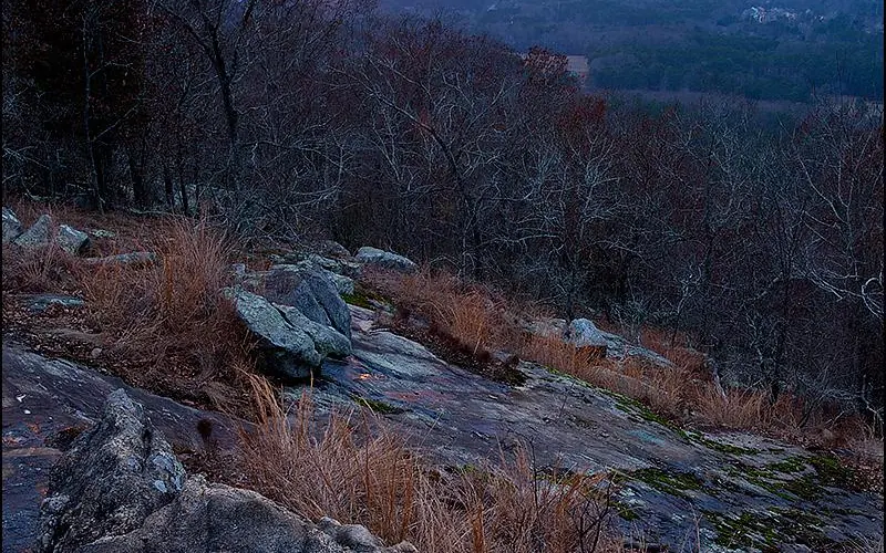 The sun sets in the background with the exposed rock of Kennesaw Mountain in the foreground.