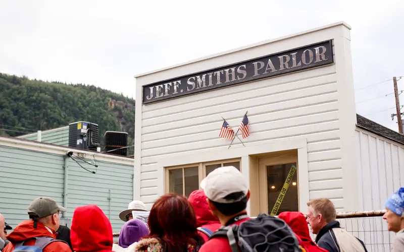People standing around a ranger in front of a building.