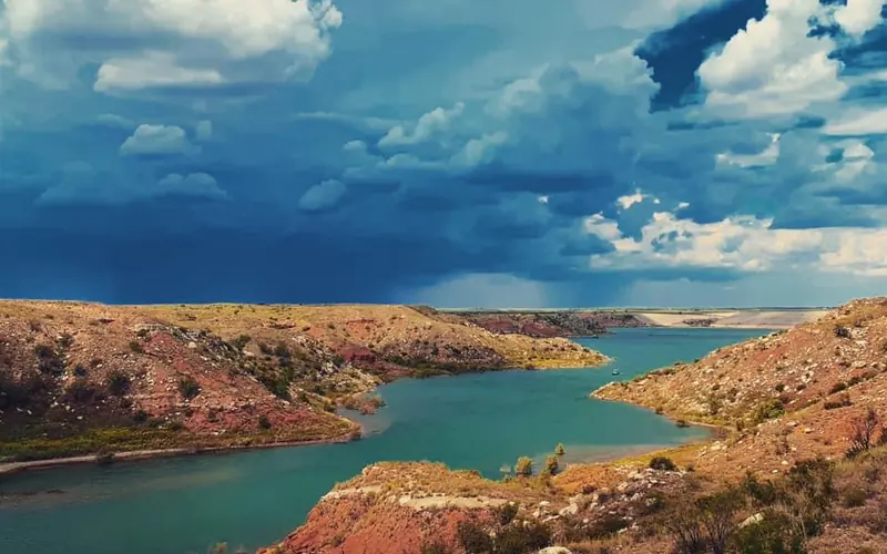 A storm coming in at Lover's Canyon.  The sky is dark blue with dark clouds.  The lake is greenish.