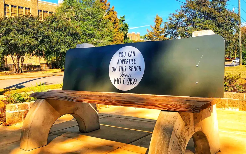 a replica of a 1950s bus bench with Central High School in the background