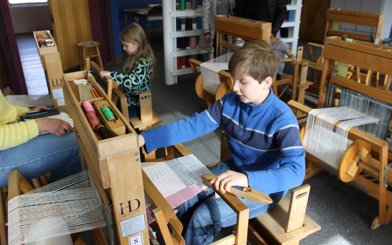 Two students weaving on the looms at the education center.