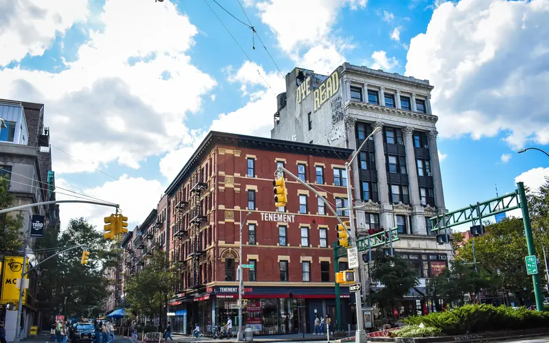 A four story red brick building against a blue sky with white puffy clouds