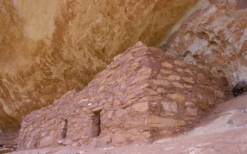 a stone structure below a rock alcove