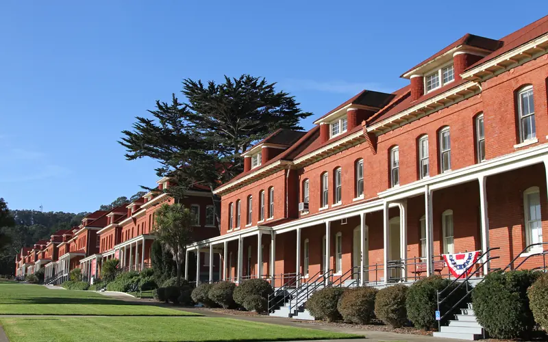 A long row of red brick barracks with green lawns in front extends into the distance.