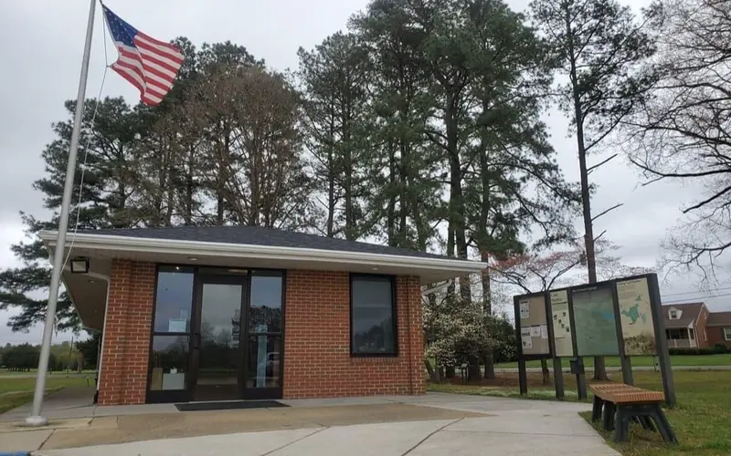 A small brick visitor center building beside a flagpole.