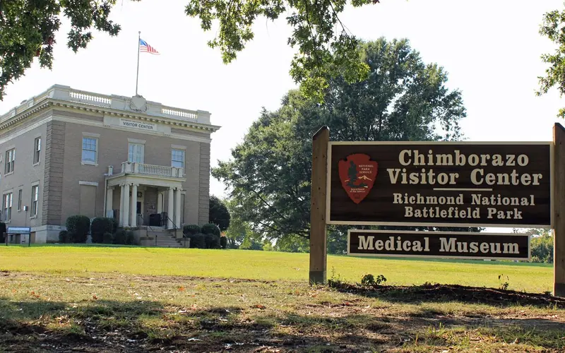 A two story gray brick building and a wooden sign reading "Chimborazo Visitor Center"
