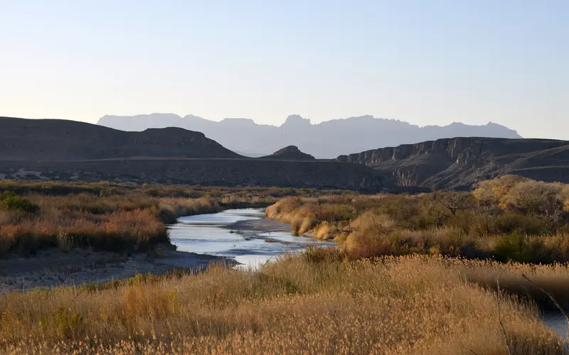 A desert river with a backdrop of mountains in the distance.