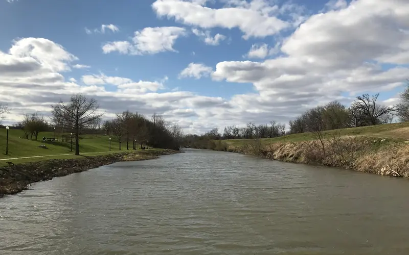 A wide river with green grass parks on the side.