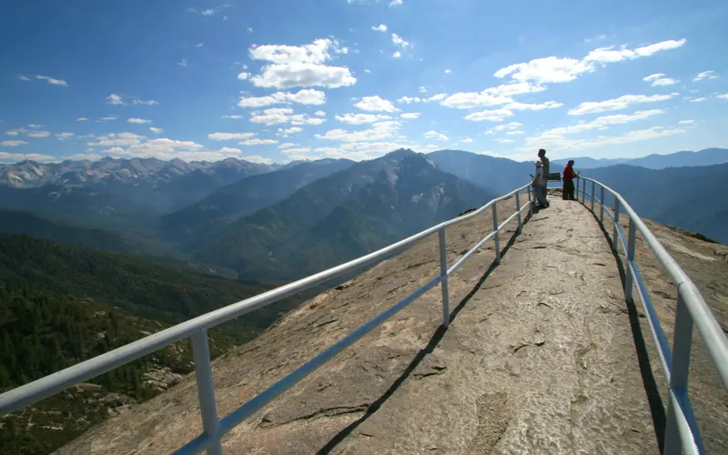 A guardrail encircles people along a narrow walkway with wide views