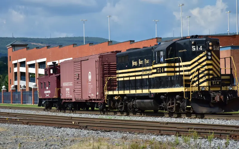 Black and yellow diesel engine 514 pulling a faded red box car and a dark red caboose