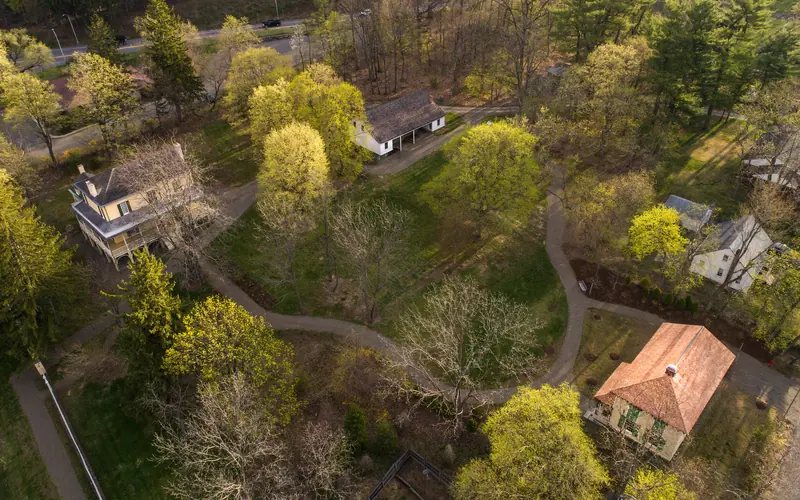 A bird's eye view of several buildings nested among trees and lawn.