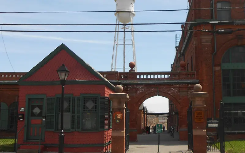 Small red building next to large brick building with a water tower in the background.