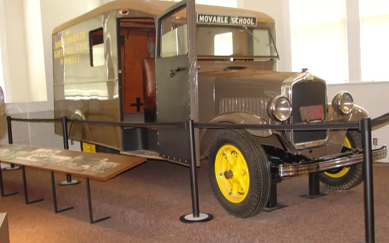 A  brown colored modified school bus with two windows