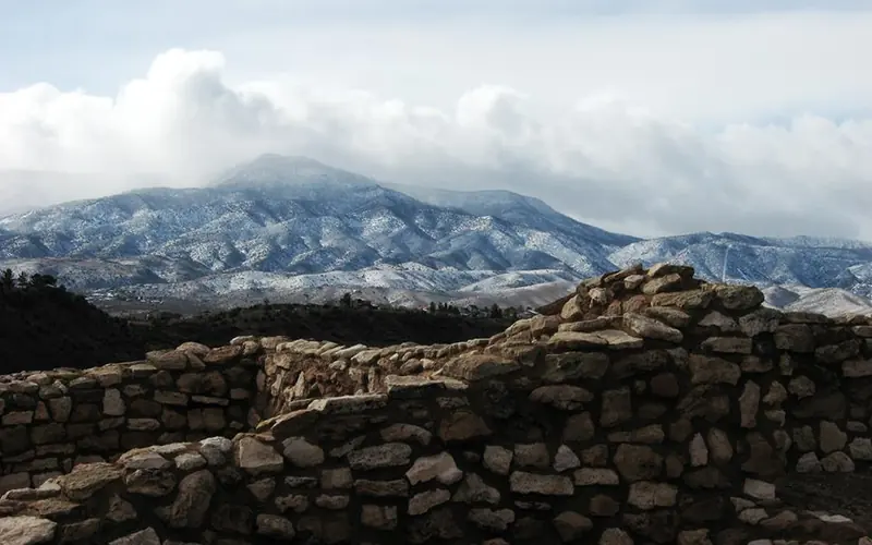 4 foot masonry walls with mountains and clouds behind them.