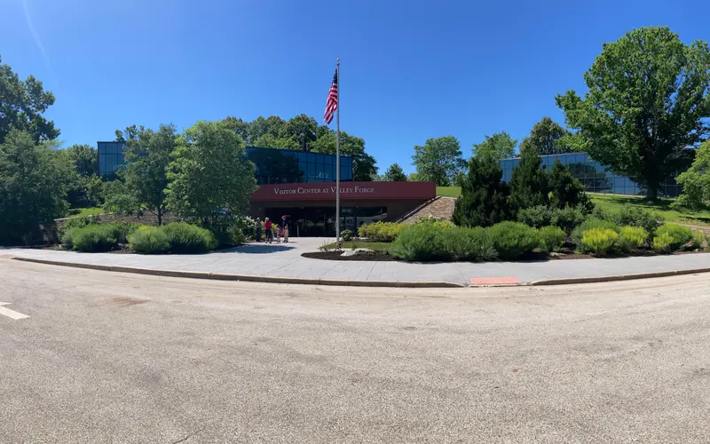 a building that extends into a hillside with a flagpole and landscaping out front
