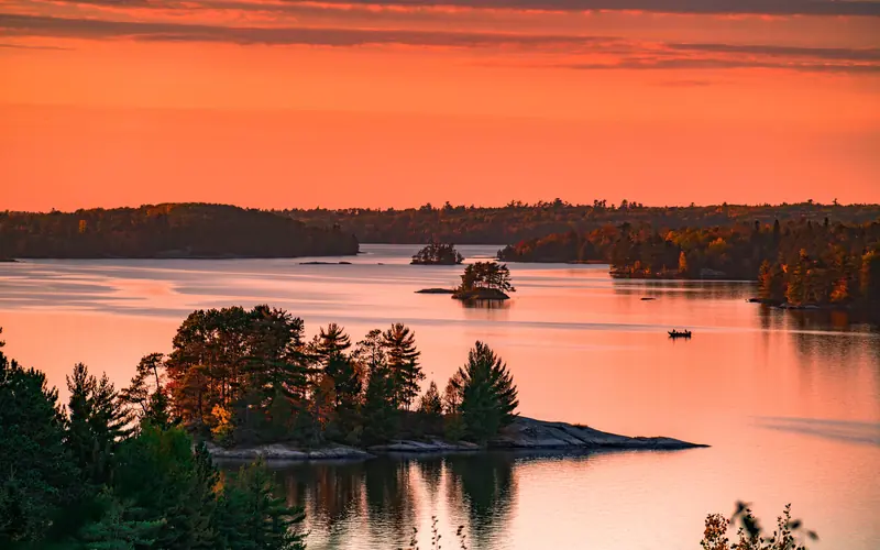 Orange tinted sky with islands scattered throughout the still lake.