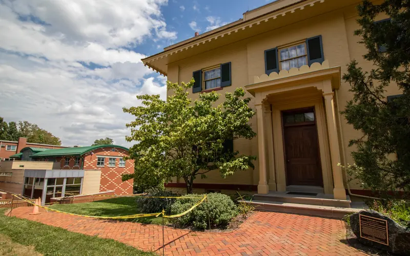 A yellow building to the right with a red brick sidewalk leading to a tan and red building