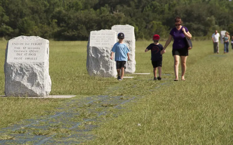 Visitors walk along the flight line where Wilbur and Orville Wright flew and landed.