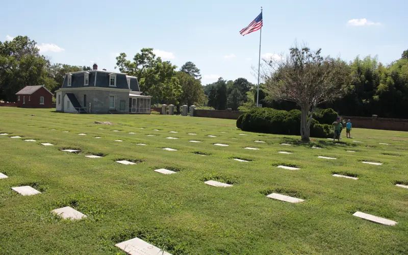 National Cemetery showing tombstones, American Flag and Cemetery Lodge in sunlight.